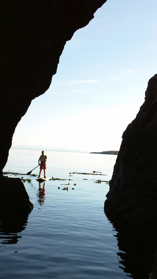 Kid on a stand up paddle board entering cave